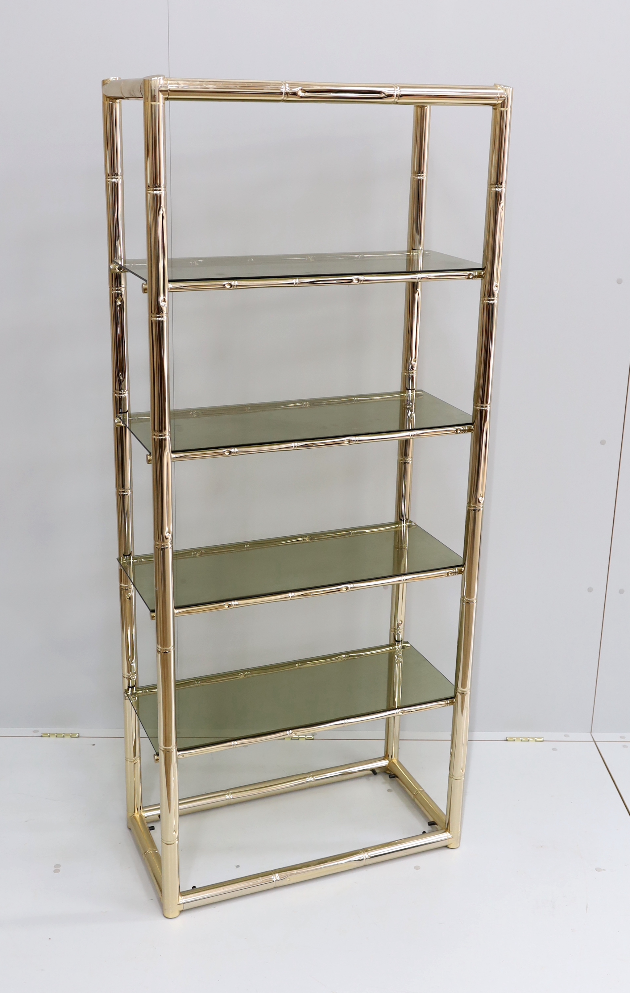 A Maison Jansen style faux bamboo brass and smoked glass five tier shelf unit, width 76cm, depth 39cm, height 180cm